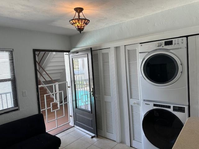 clothes washing area featuring light tile flooring and stacked washer / drying machine