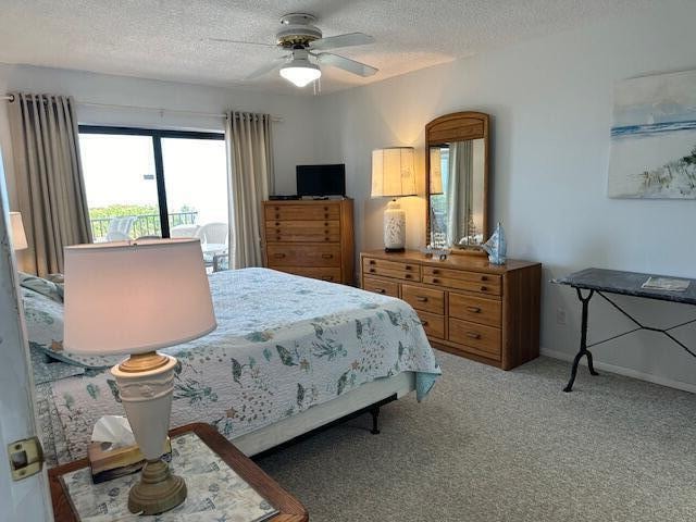 carpeted bedroom featuring ceiling fan and a textured ceiling