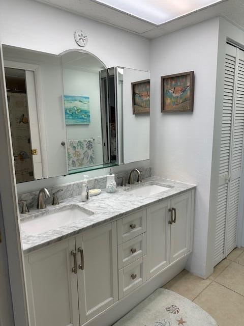 bathroom with dual bowl vanity, tile flooring, and walk in shower