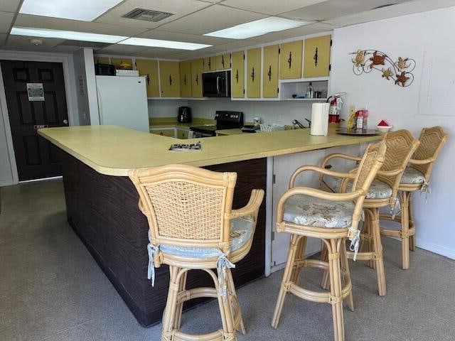 kitchen featuring black appliances, kitchen peninsula, and a drop ceiling