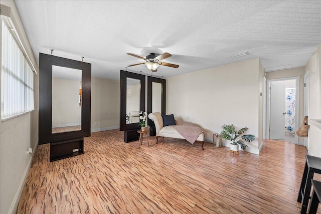 sitting room featuring light hardwood / wood-style floors, a textured ceiling, and ceiling fan