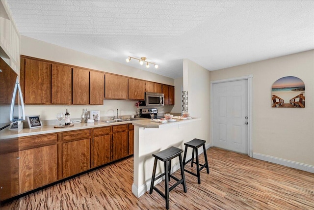 kitchen featuring a kitchen bar, light hardwood / wood-style flooring, a textured ceiling, rail lighting, and stove