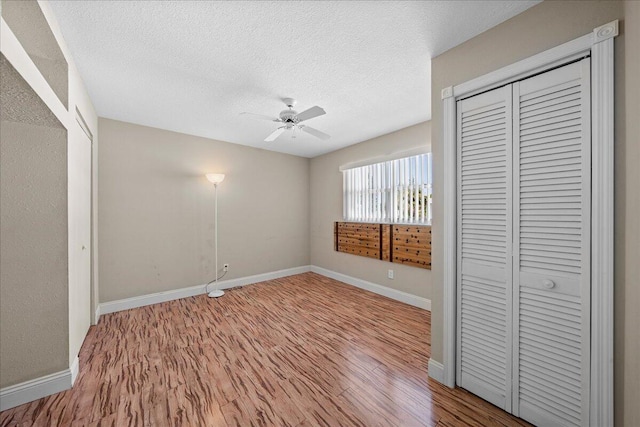 unfurnished bedroom featuring a closet, light hardwood / wood-style floors, ceiling fan, and a textured ceiling