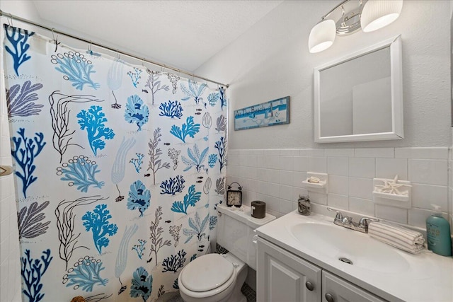 bathroom featuring toilet, a textured ceiling, tile walls, vanity with extensive cabinet space, and backsplash