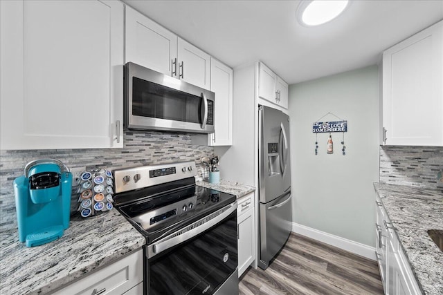 kitchen featuring tasteful backsplash, light stone counters, stainless steel appliances, dark hardwood / wood-style floors, and white cabinetry