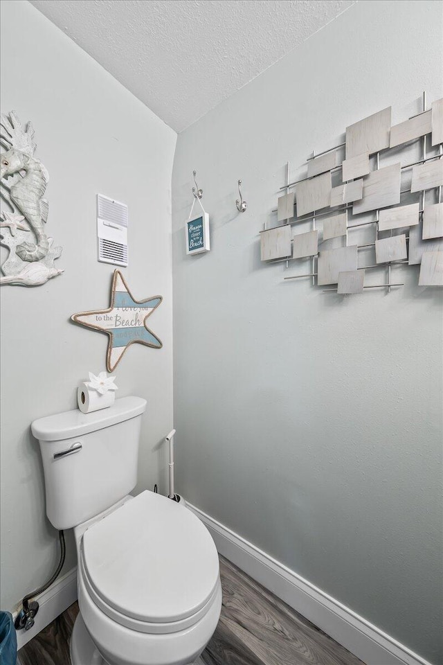 bathroom with toilet, wood-type flooring, and a textured ceiling