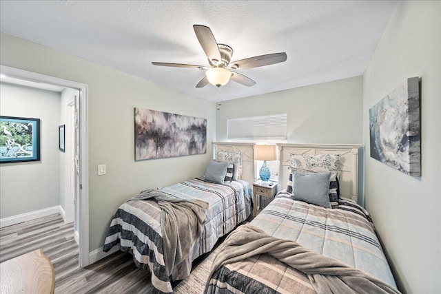 bedroom with a textured ceiling, hardwood / wood-style flooring, and ceiling fan