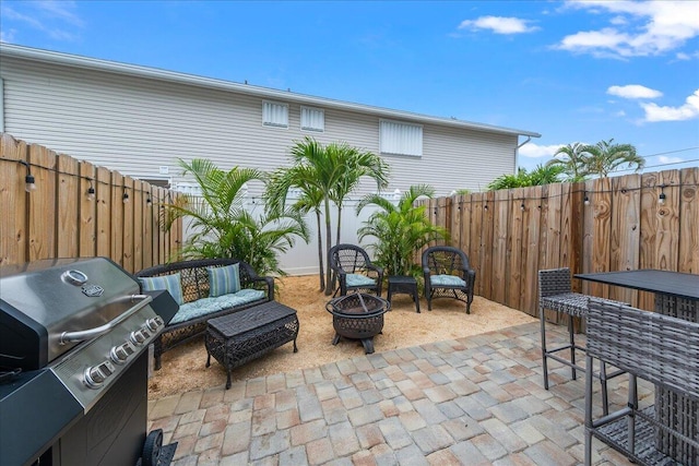 view of patio / terrace with exterior bar, an outdoor living space with a fire pit, and a grill