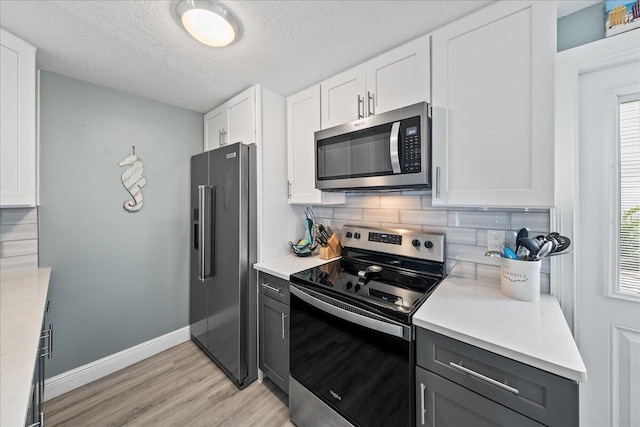 kitchen with stainless steel appliances, light hardwood / wood-style floors, a textured ceiling, decorative backsplash, and white cabinets