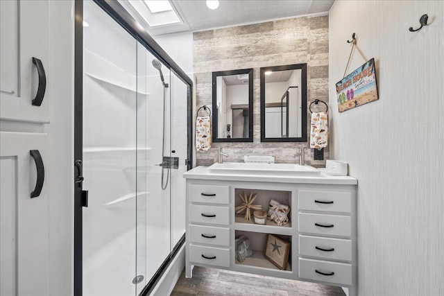 bathroom featuring a skylight, hardwood / wood-style floors, vanity, and a shower with shower door