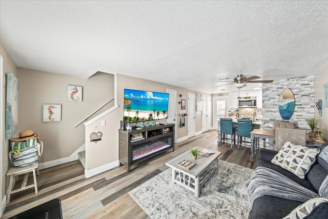 living room with ceiling fan, hardwood / wood-style floors, and a textured ceiling