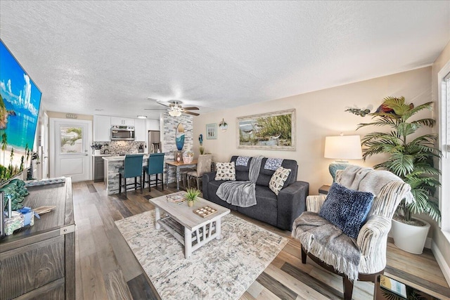 living room featuring a textured ceiling, dark hardwood / wood-style floors, and ceiling fan