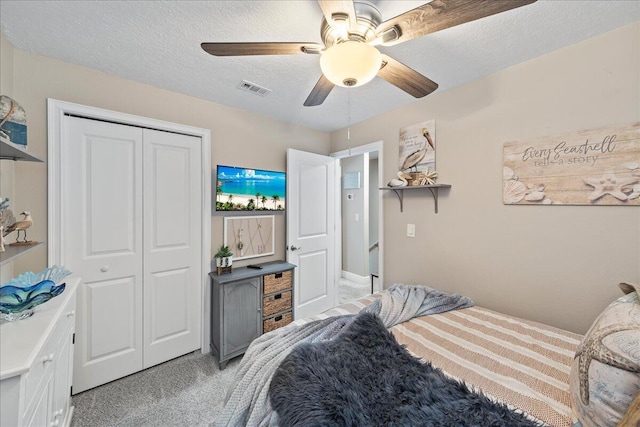 carpeted bedroom featuring a textured ceiling, a closet, and ceiling fan