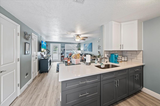 kitchen featuring tasteful backsplash, sink, white cabinets, and light hardwood / wood-style flooring