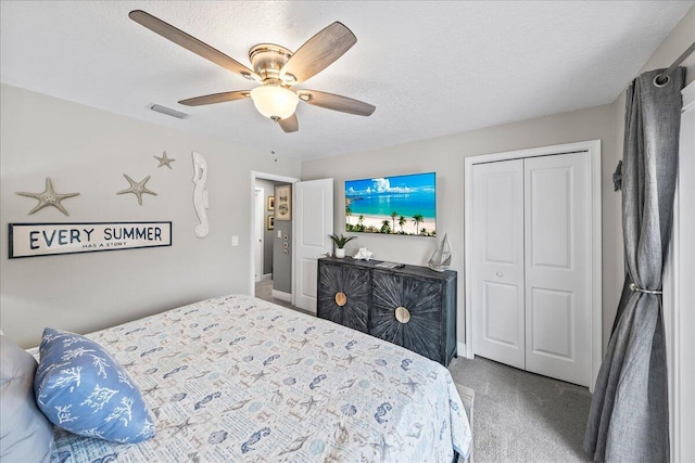 carpeted bedroom with ceiling fan, a closet, and a textured ceiling