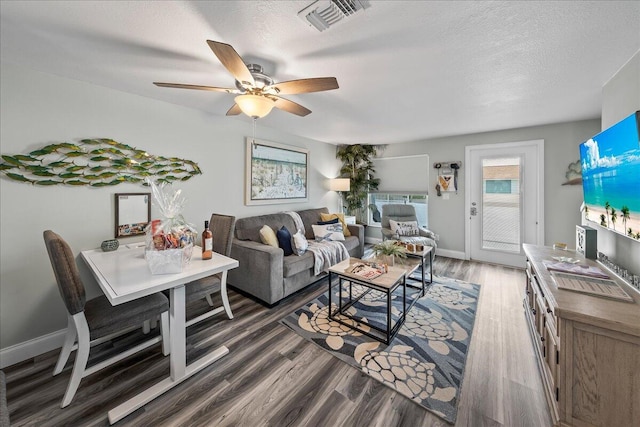 living room with a textured ceiling, dark hardwood / wood-style floors, and ceiling fan