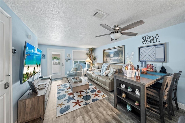 living room featuring ceiling fan, wood-type flooring, and a textured ceiling