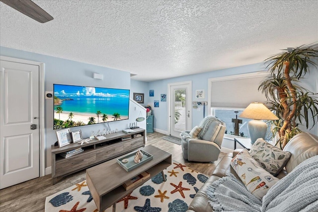 living room featuring a textured ceiling, light hardwood / wood-style floors, and ceiling fan