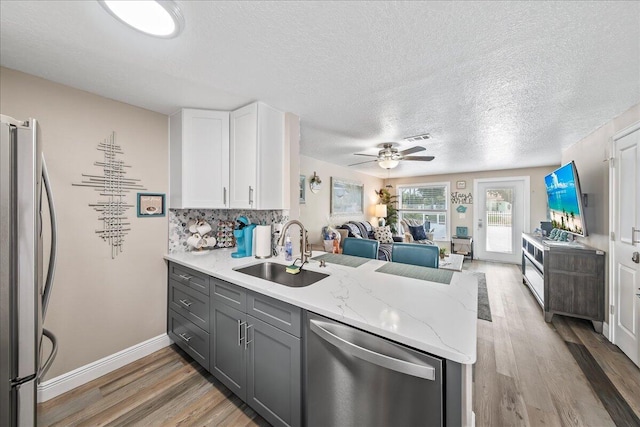 kitchen featuring decorative backsplash, appliances with stainless steel finishes, sink, hardwood / wood-style flooring, and white cabinetry