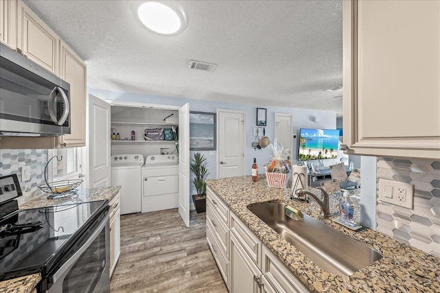 kitchen featuring light stone countertops, sink, separate washer and dryer, a textured ceiling, and appliances with stainless steel finishes