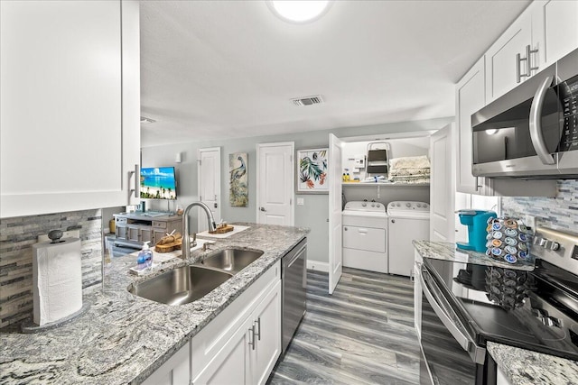 kitchen featuring white cabinets, washer and dryer, sink, and appliances with stainless steel finishes