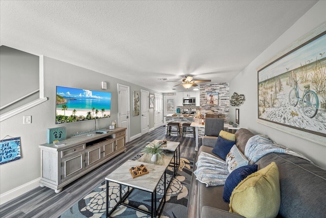 living room with dark hardwood / wood-style flooring, a textured ceiling, and ceiling fan