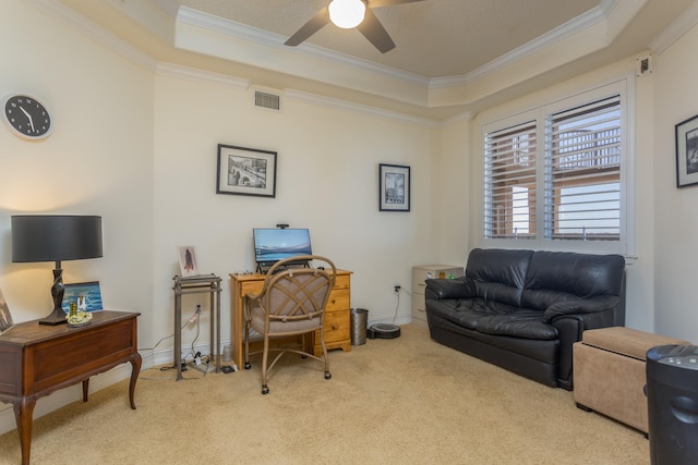 carpeted office space with a raised ceiling, crown molding, and ceiling fan