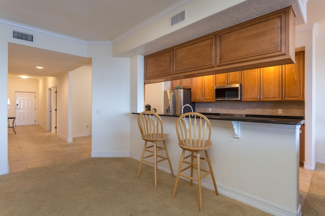 kitchen featuring stainless steel appliances, a breakfast bar, ornamental molding, light carpet, and backsplash