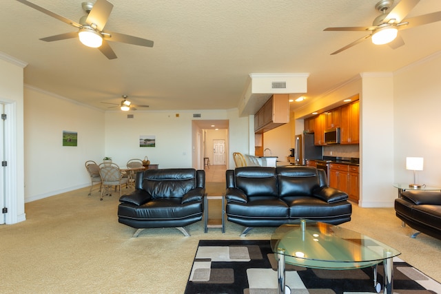 living room with a textured ceiling, ornamental molding, light colored carpet, and ceiling fan