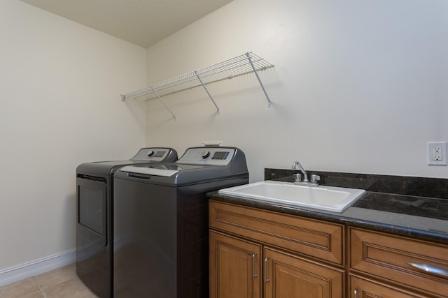 laundry room featuring washing machine and clothes dryer, cabinets, sink, and light tile floors