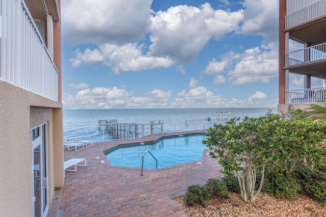 view of swimming pool with a water view and a patio area