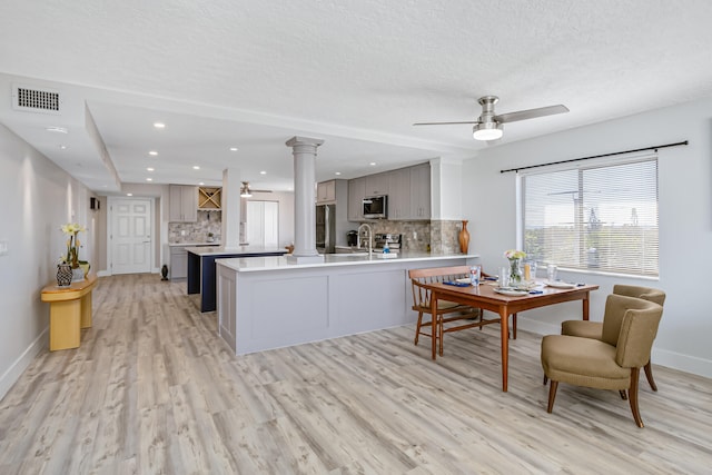 interior space with ceiling fan, sink, light hardwood / wood-style flooring, a textured ceiling, and ornate columns