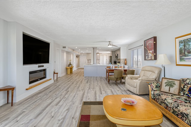 living room with a textured ceiling, light hardwood / wood-style floors, ceiling fan, and sink