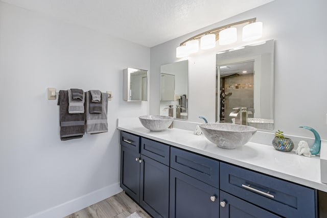 bathroom with hardwood / wood-style floors, a textured ceiling, and double sink vanity