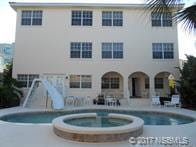 rear view of property with a pool with hot tub and a patio area