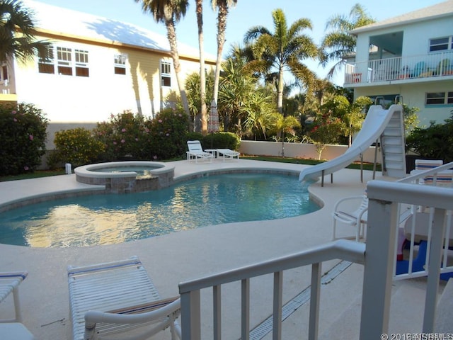 view of pool featuring an in ground hot tub, a water slide, and a patio area