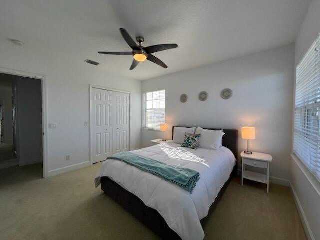 carpeted bedroom featuring a closet and ceiling fan