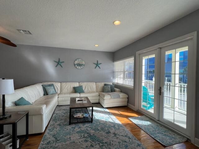 living room featuring french doors, a textured ceiling, and hardwood / wood-style flooring