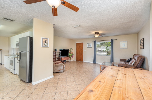 living room with a textured ceiling, light tile flooring, and ceiling fan