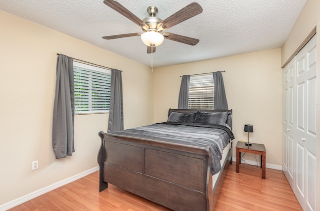 bedroom with a closet, a textured ceiling, ceiling fan, and light wood-type flooring