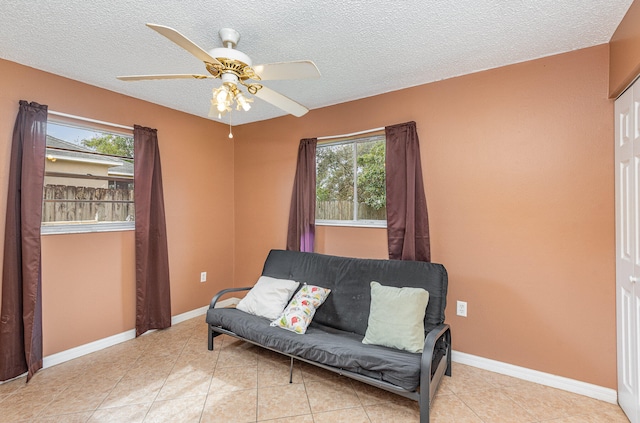 sitting room with ceiling fan, light tile floors, and a wealth of natural light