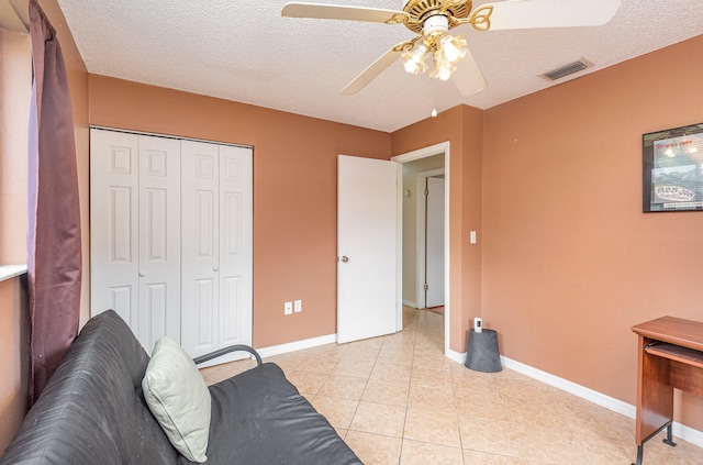 tiled living room with a textured ceiling and ceiling fan