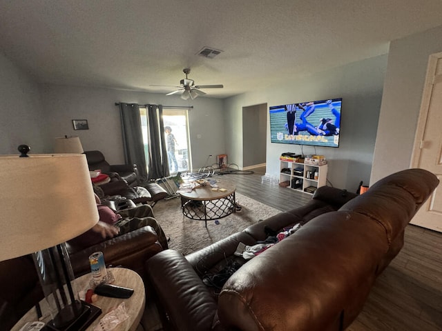 living room featuring hardwood / wood-style floors, ceiling fan, and a textured ceiling