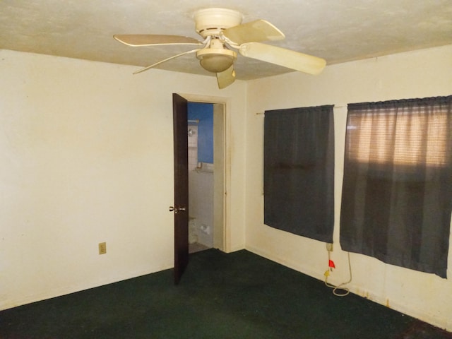 spare room with dark carpet and ceiling fan