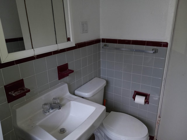 bathroom with tile walls, toilet, backsplash, and sink