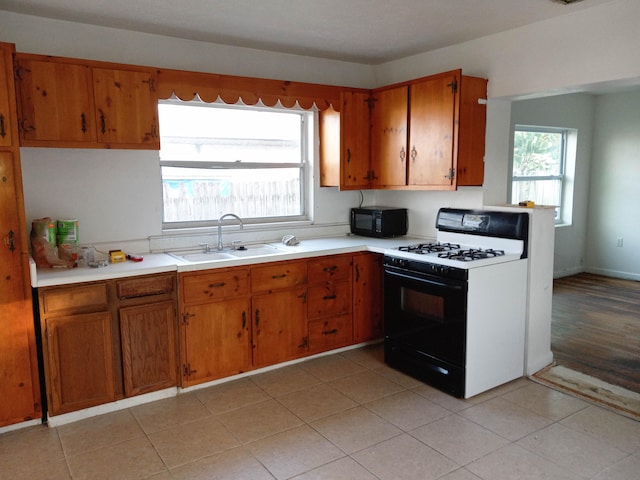 kitchen featuring white range with gas cooktop, light tile floors, and sink