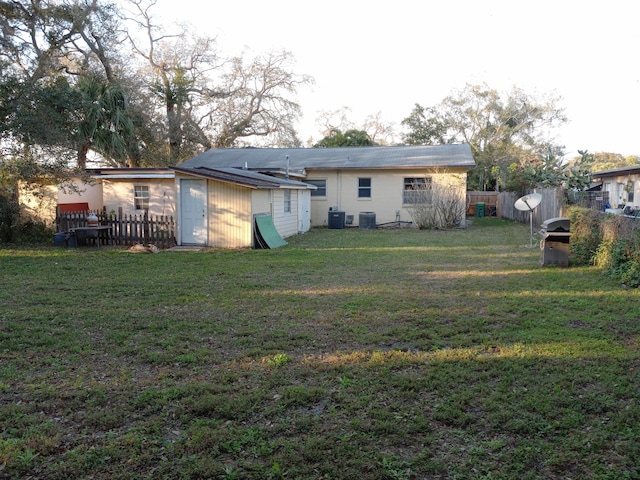 rear view of property featuring a lawn and central AC unit