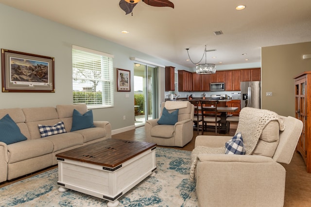 living room with ceiling fan with notable chandelier