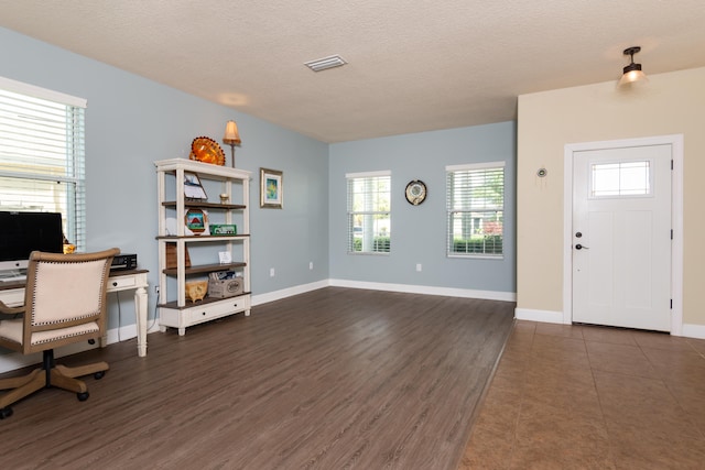 home office with dark hardwood / wood-style flooring and a textured ceiling