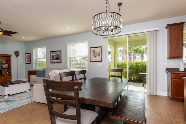 dining room with a textured ceiling, light tile patterned flooring, and ceiling fan with notable chandelier